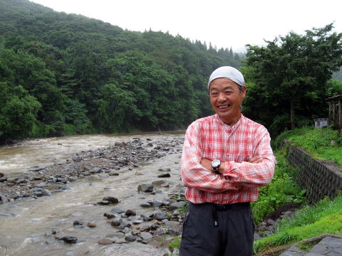 赤石川を背にした吉川隆さんの写真